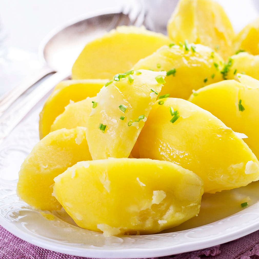 Traditional boiled potatoes with chives service es close-up on a classic design plate