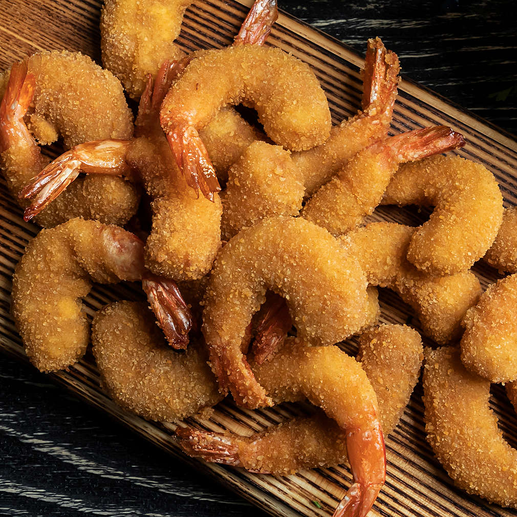 fried breaded shrimps, mussels served with lime on wooden board, delicious deep, red, white sauce
