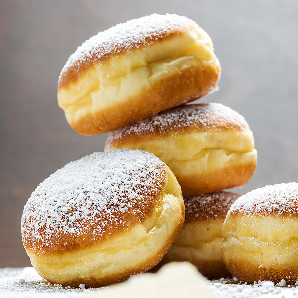 Close-up of donuts (Berlin pancakes) dusted with powdered sugar served on a rustic wooden table