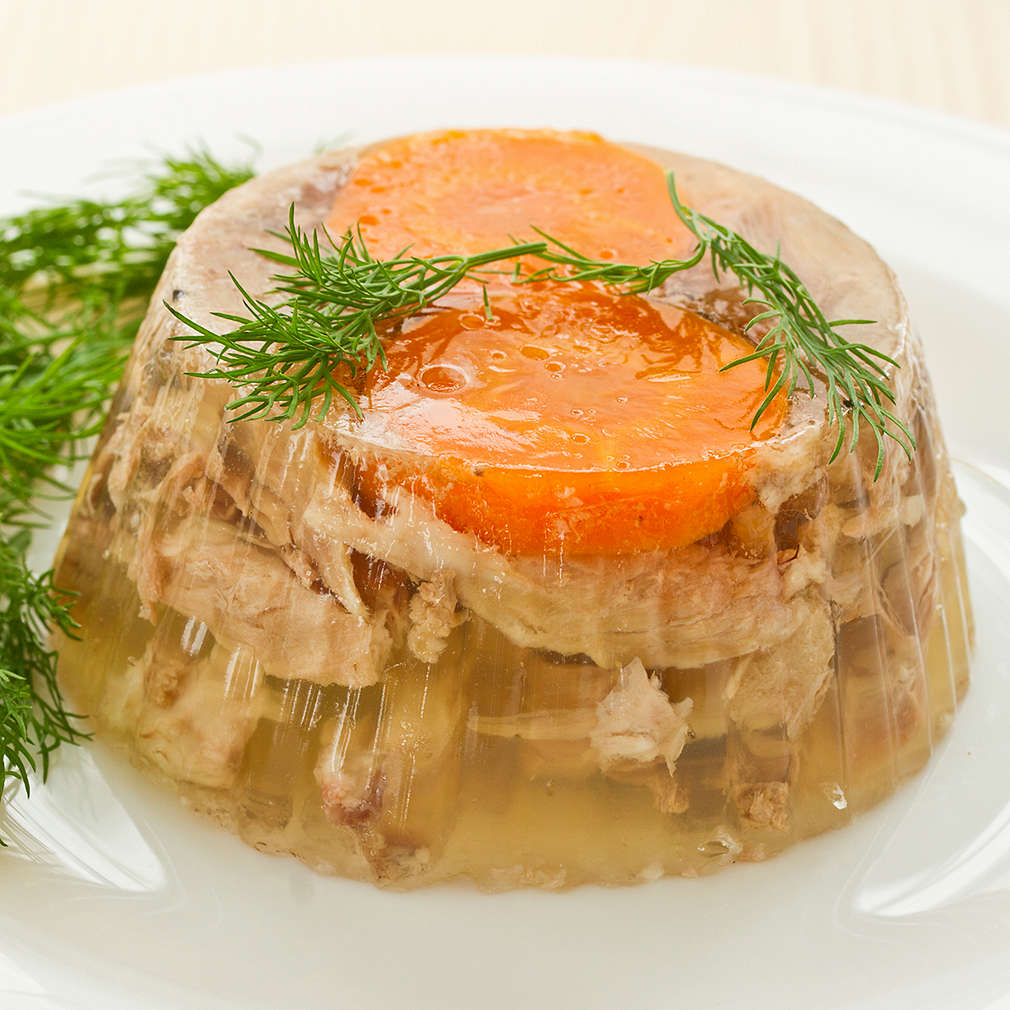 jellied meat and vegetables on a white plate