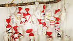 Na debeloj grani pričvršćenoj na bijelom zidu visi samostalno izrađeni i obojeni adventski kalendar od crvenih i bijelih papirnatih čaša.