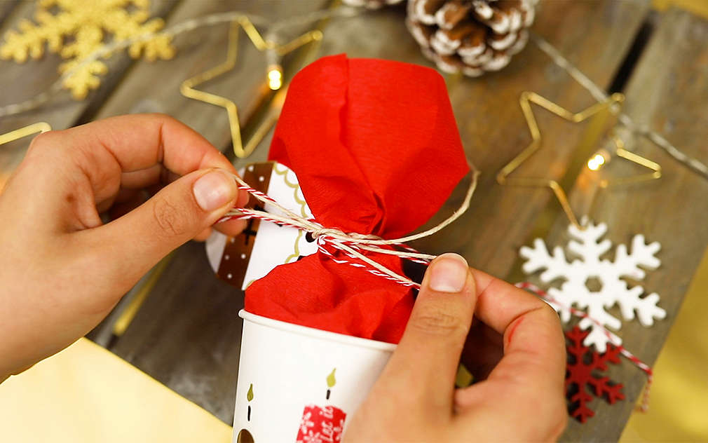 Po naplnění se kelímky zavřou tak, že se červený papír převáže stužkou.