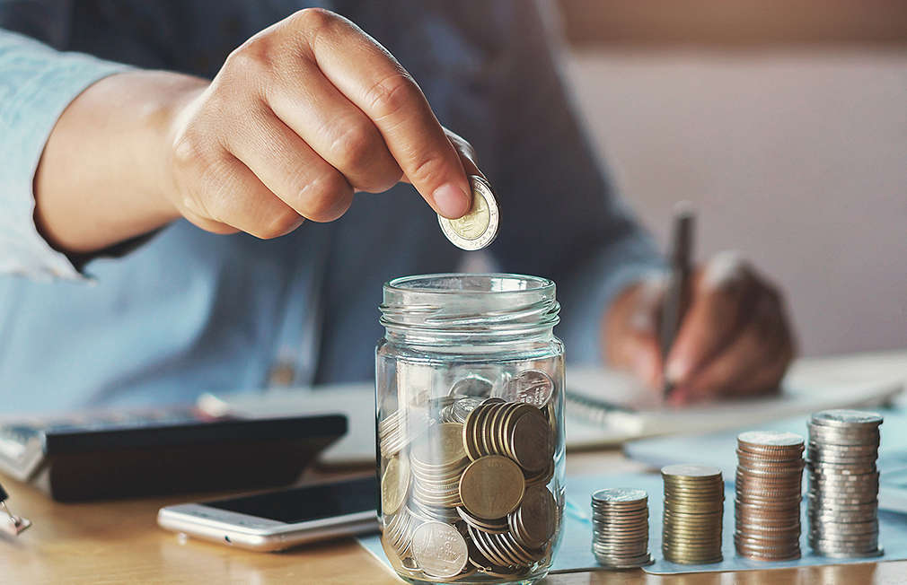 Someone throws a coin into a jar with more coins