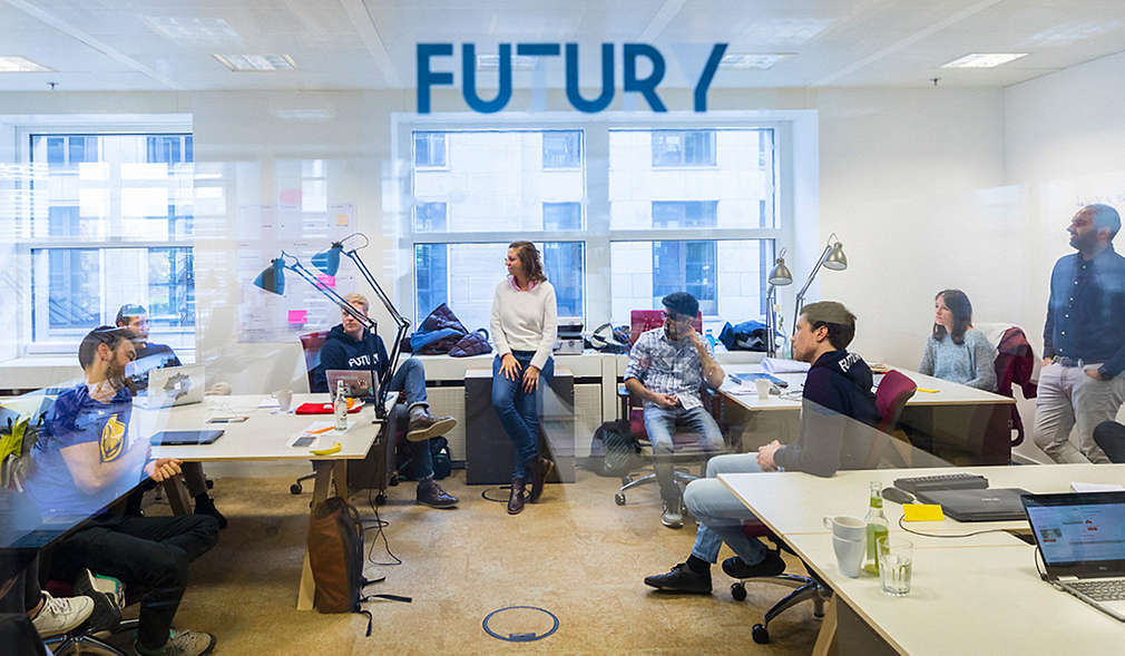 Logo: FUTURY; Abbildung: mehrere Personen in einem Raum