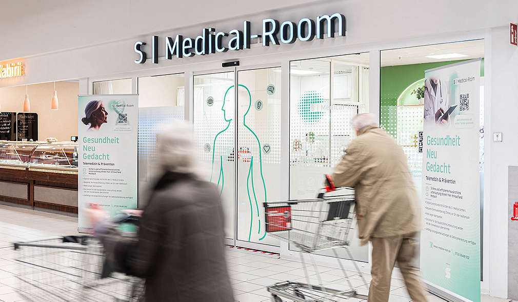 Abbildung: S | Medical-Room in Kaufland-Filiale; Menschen mit Einkaufswägen am Vorbeigehen