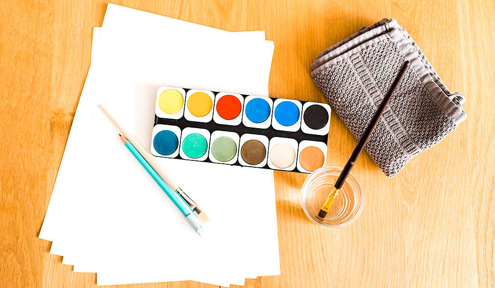 Pinsel, Stift, Wasserfarben, Handtuch und Papier zum Anfertigen eines Hand- oder Fußabdrucks