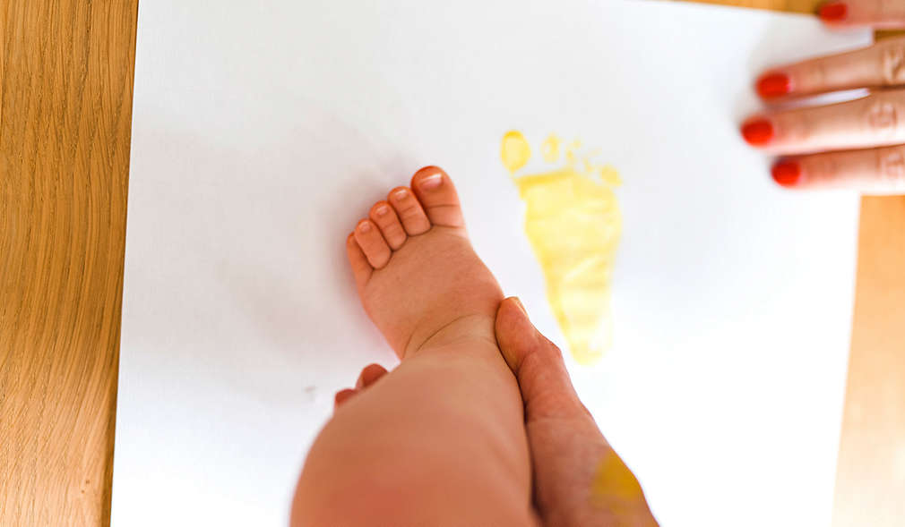 Von einem Baby werden Abdrücke der Füße angefertigt