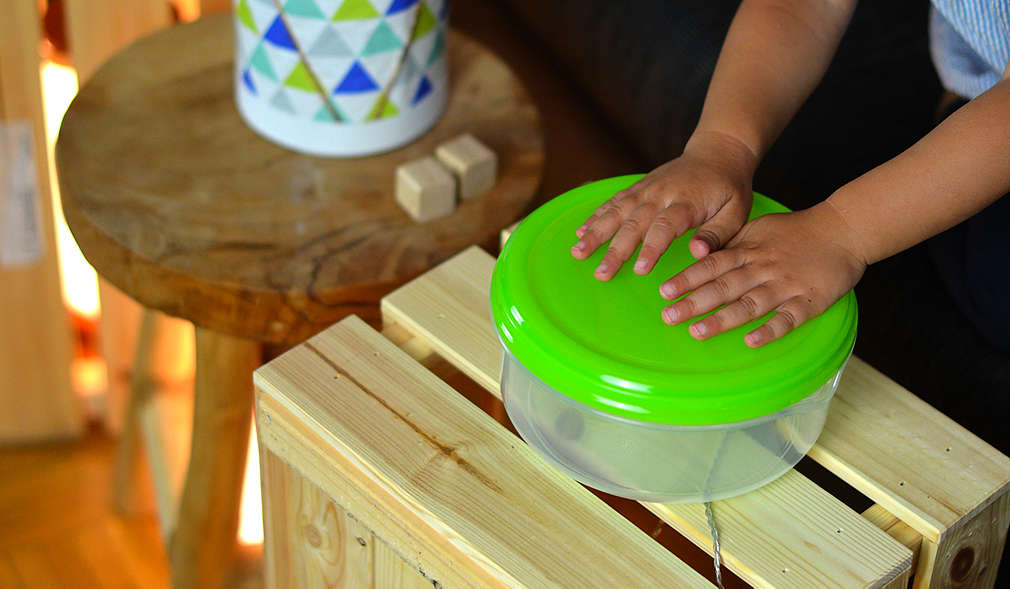 Kinderhände trommeln auf Handtrommel aus Plastikdose gebastelt