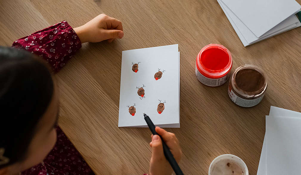 Kind bemalt eine selbstgebastelte Karte