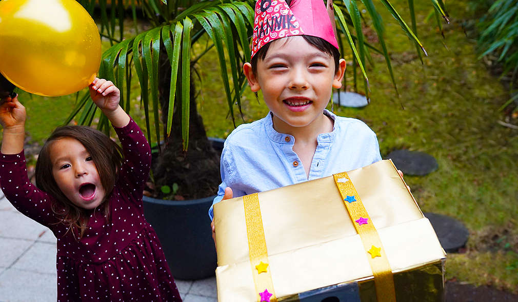 Ein Junge trägt eine Kiste, ein Mädchen jubelt.