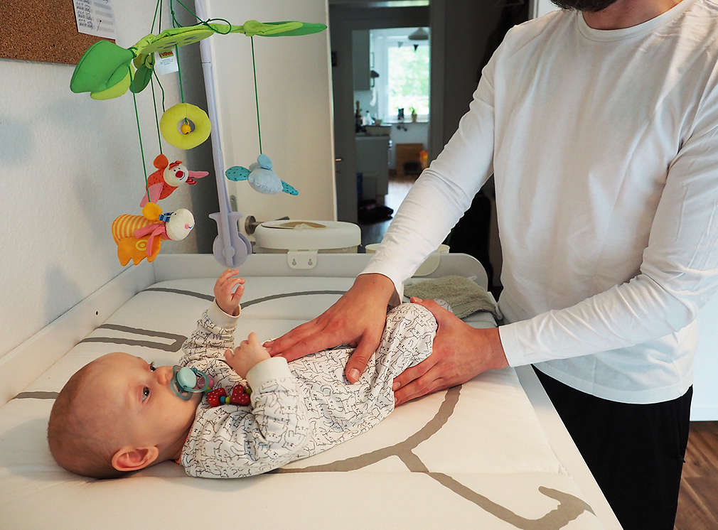 Vater massiert Bäuchlein von Baby