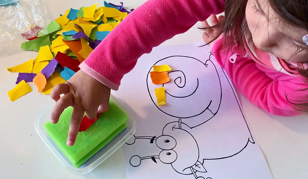 Mädchen bastelt ein buntes Bild aus Papierschnipseln