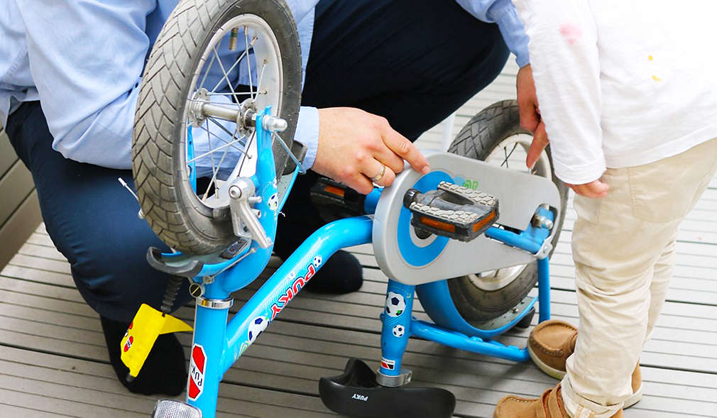 Vater zeigt Kind wie Fahrrad funktioniert