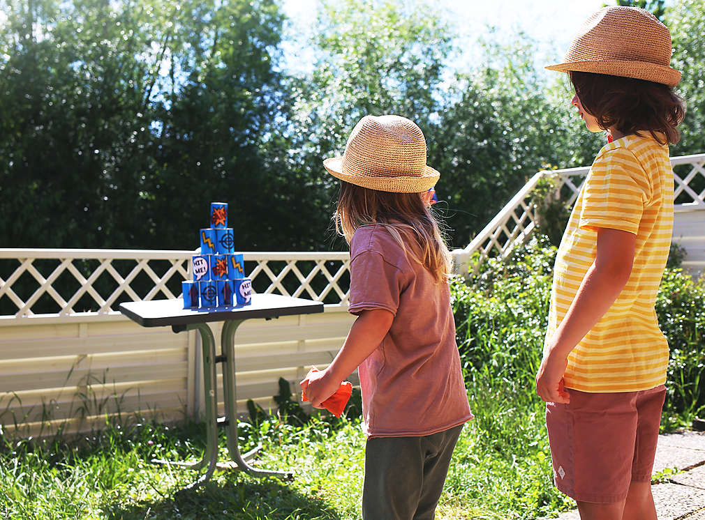 Zwei Kinder im Garten beim Dosenwerfen