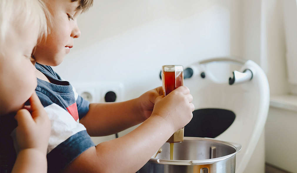 Kind gibt Honig in eine Schüssel