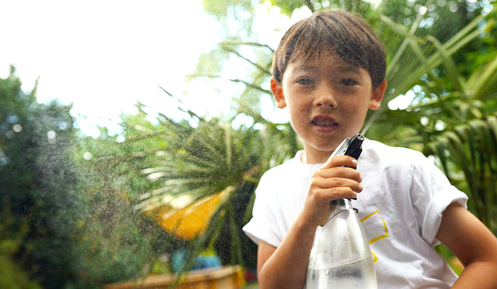 Kind hält eine Sprühflasche mit Wasser gefüllt in der Hand