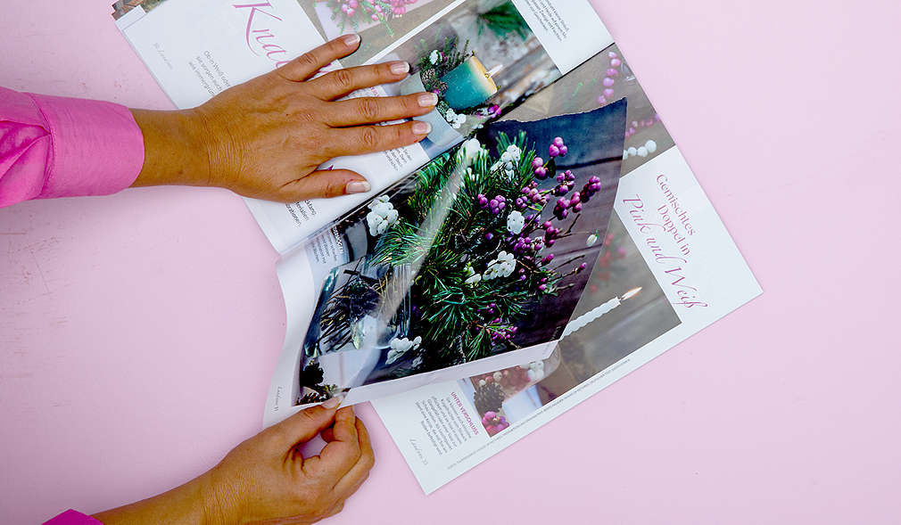 Frau reißt Blatt Papier aus Zeitschrift