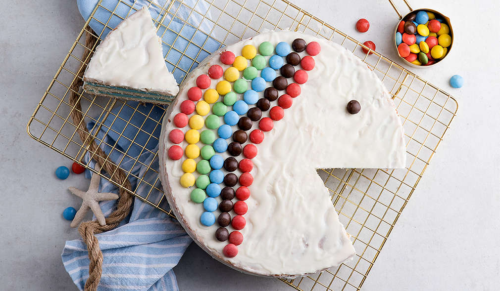 Runder Kuchen mit Kuvertüre und Schokolinsen mit Augen und Maul eines Fisches