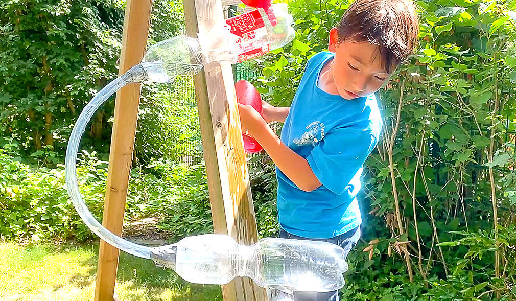 Junge baut Wasserbahn aus Flaschen