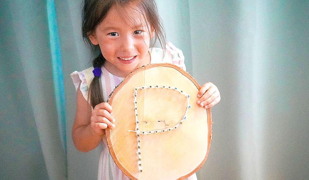 Mädchen hält ein selbst gemachtes Fadenbild in der Hand