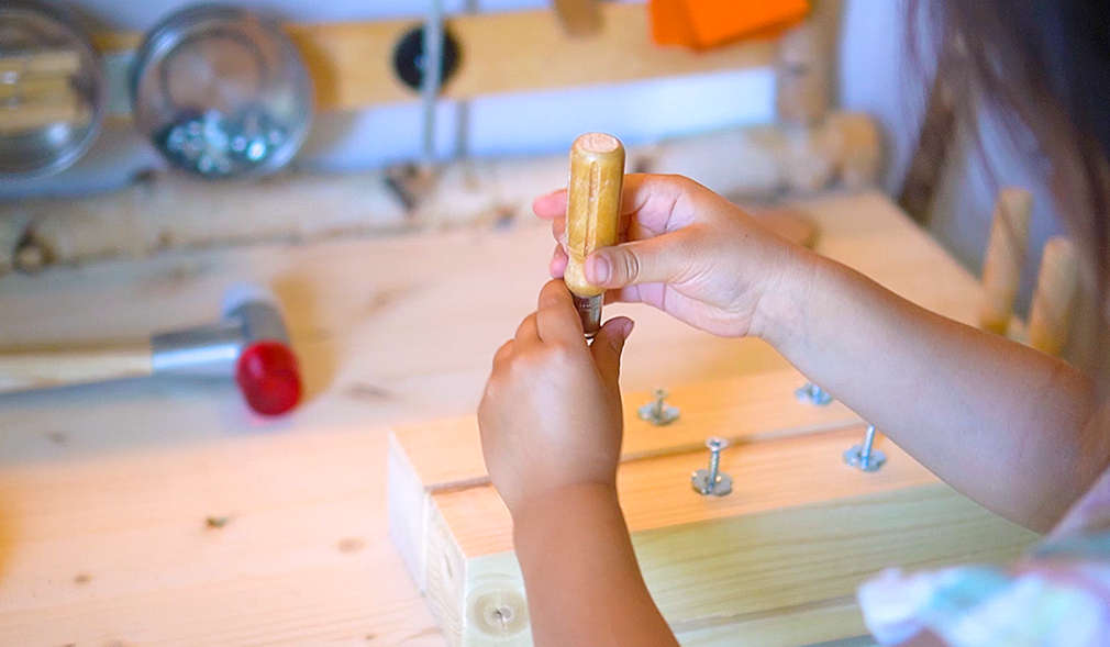 Mädchen dreht Schrauben in ein Schraubbrett