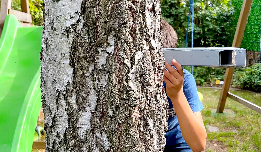 Kind versteckt sich hinter Baum