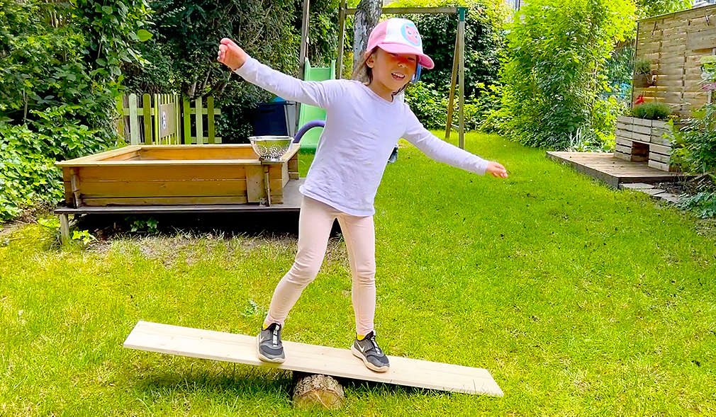 Mädchen balanciert auf einem Holzbrett