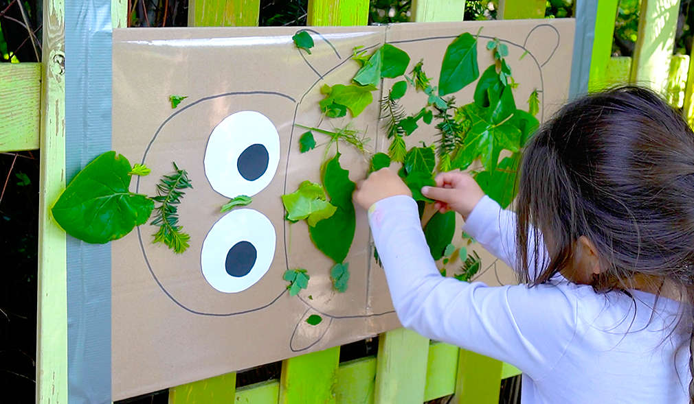 Mädchen klebt Blätter auf ein Plakat