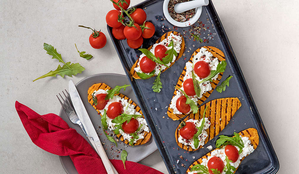 Süßkartoffelscheiben belegt mit Frischkäse, Rucola und Tomaten