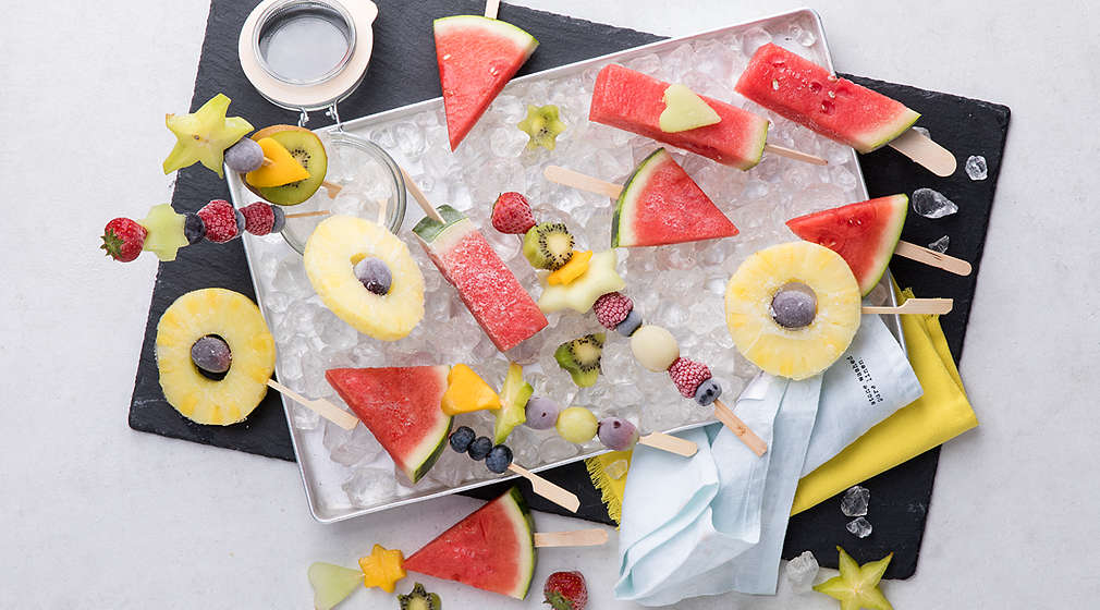 Trauben, Heidelbeeren und Brombeeren am Spieß sowie in Scheiben geschnittene Ananas und Wassermelone