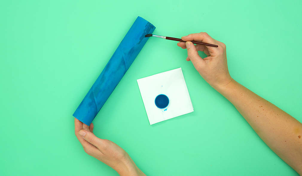 Das Bemalen der Küchenrolle mit einem Pinsel