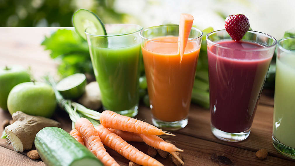 Verschiedene Sorten an Smoothies mit Obst und Gemüse auf einem Tisch