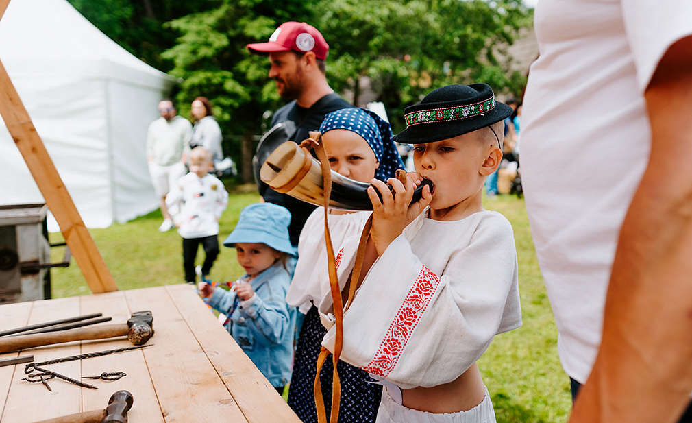 Chlapec v kroji fúka do rohu