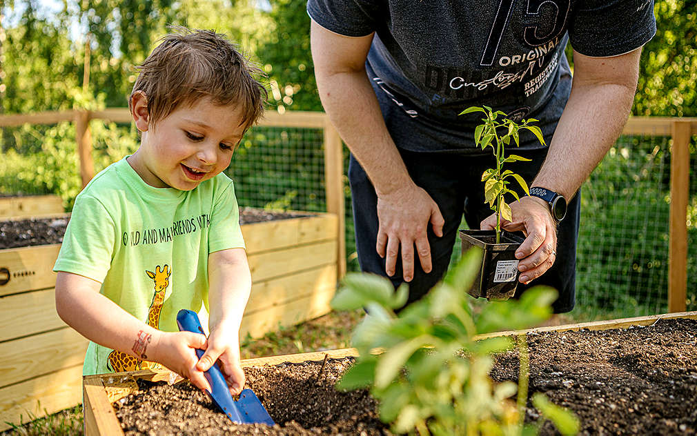 Malý chlapec dělá lopatkou díru do hlíny.