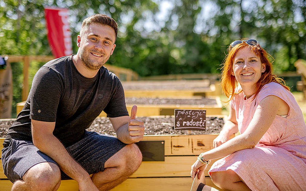 Mladý muž a žena u vyvýčených záhonů v komunitní zahradě.
