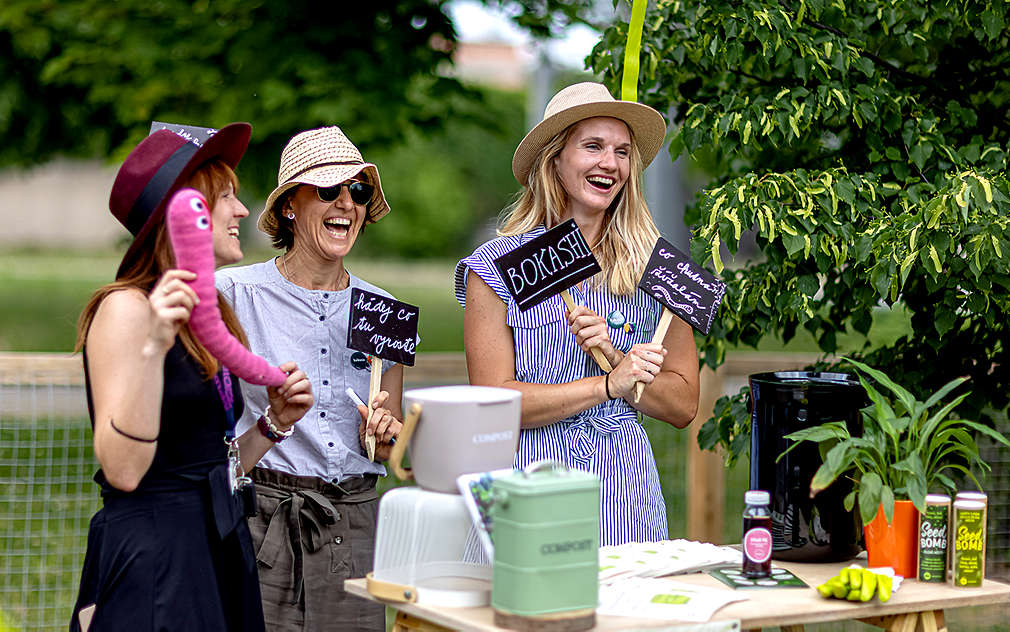 Mladé usměvavé ženy se baví v komunitní zahradě.