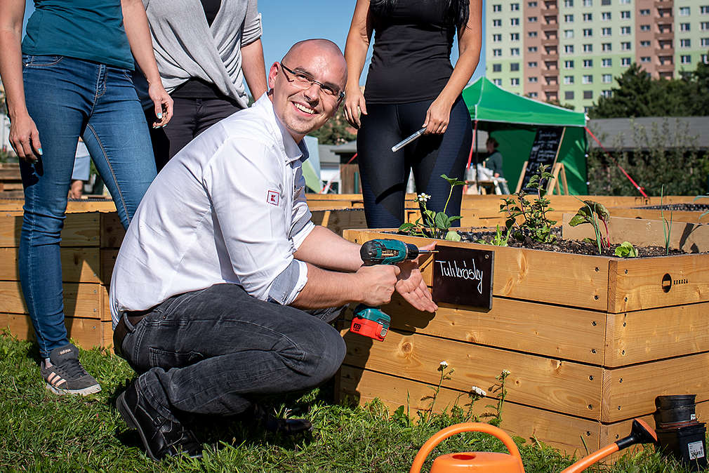 Muž přidělává na záhon jmenovku.