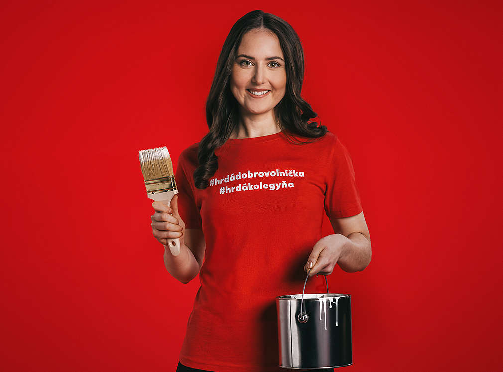 Zamestnankyňa Kauflandu drží v jednej ruke nádobu s farbou a v druhej ruke štetec