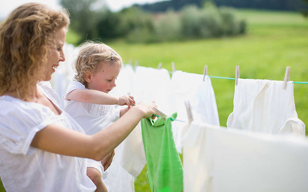 Matka vešia bielizeň na šnúru so svojím dieťaťom