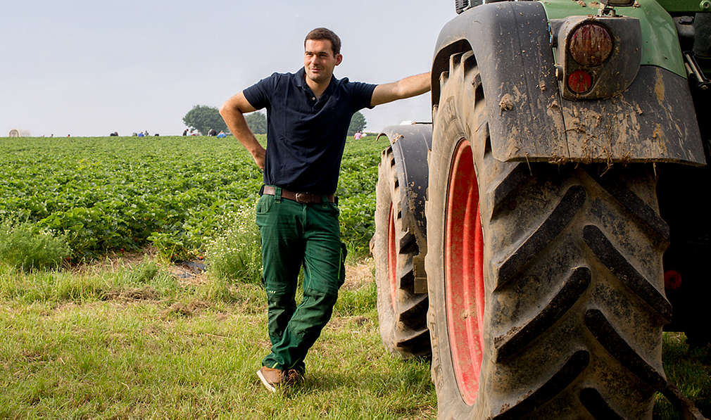 Landwirt lehnt an Traktor