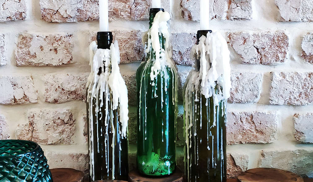 Drei Flaschenkerzen aus grünem Glas mit weißer Kerze 