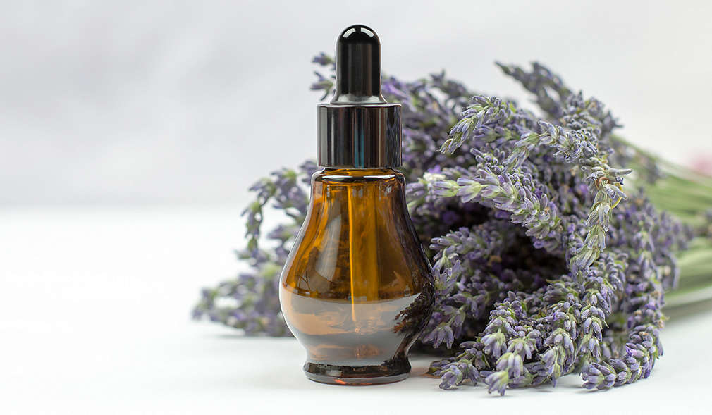Selbst gemachtes Lavendelöl in einer braunen Pipettenflasche, daneben ein Bund Lavendel