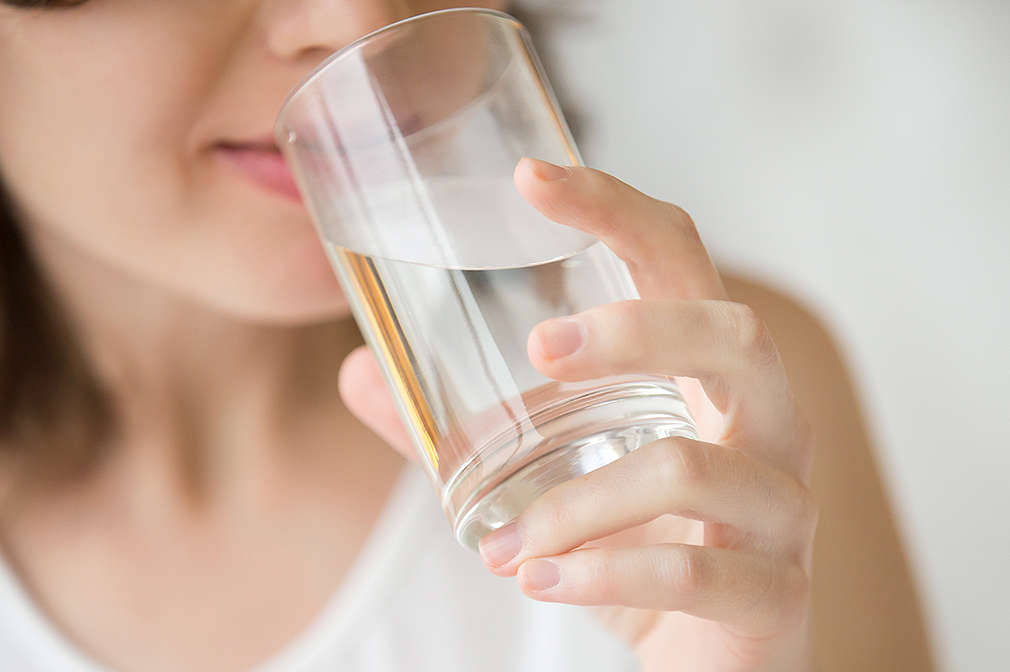 Eine Frau trinkt aus einem Wasserglas