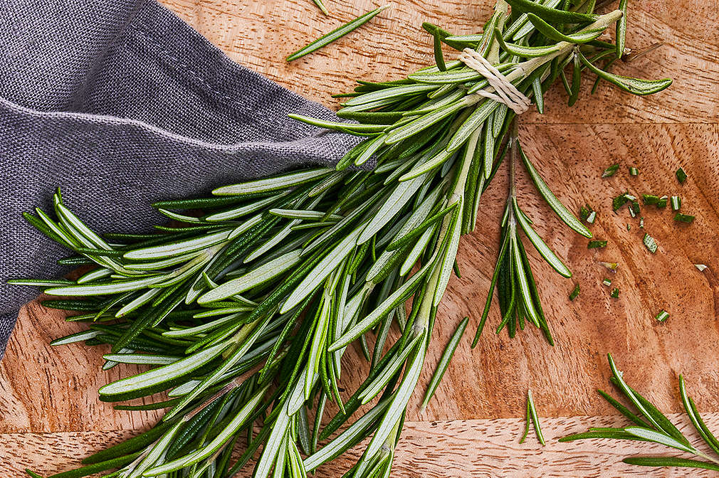 Rosmarinzweige in einem Bündel auf einem Holzbrett