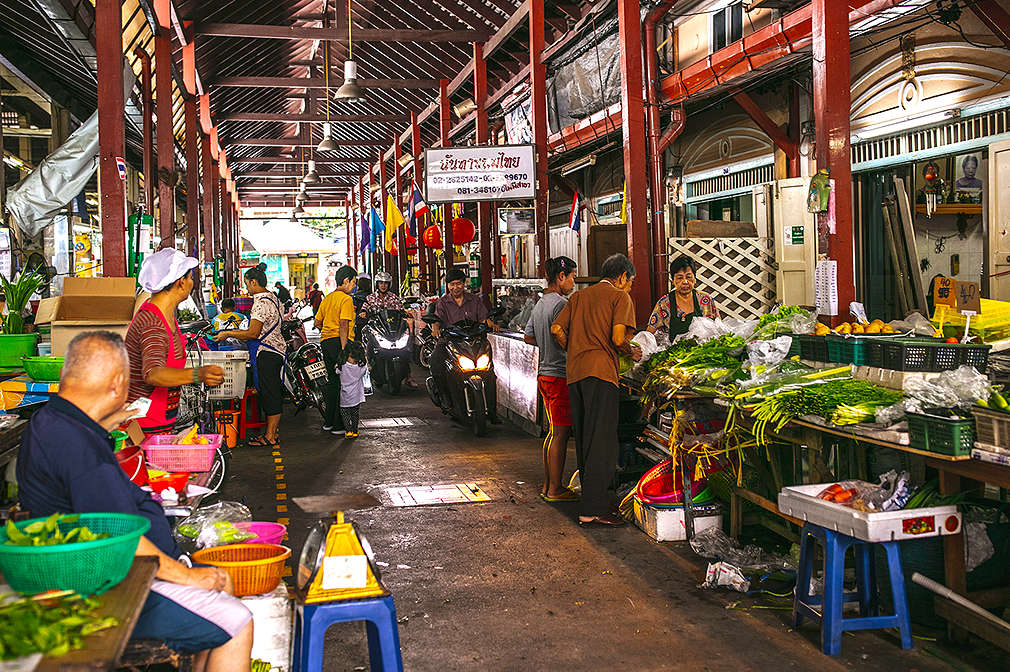 Zwei Reihen von Marktständen mit frischem Obst und Gemüse im überdachten Nang Loeng Market in Bangkok