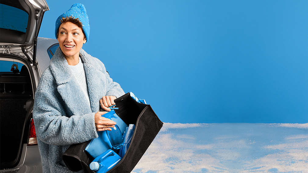 Frau packt verschiedene Autopflegemittel in eine Tasche