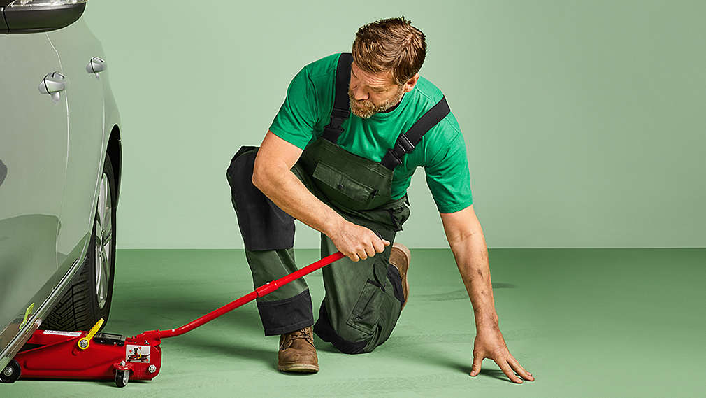 Mann platziert einen Wagenheber unter einem Auto