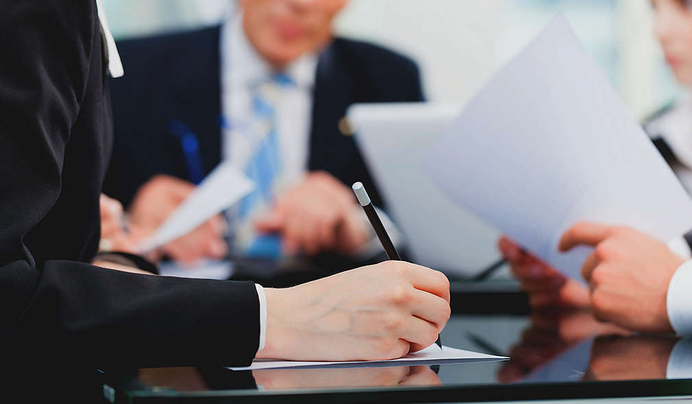 Muži v oblecích jednají a podepisují dokumenty.