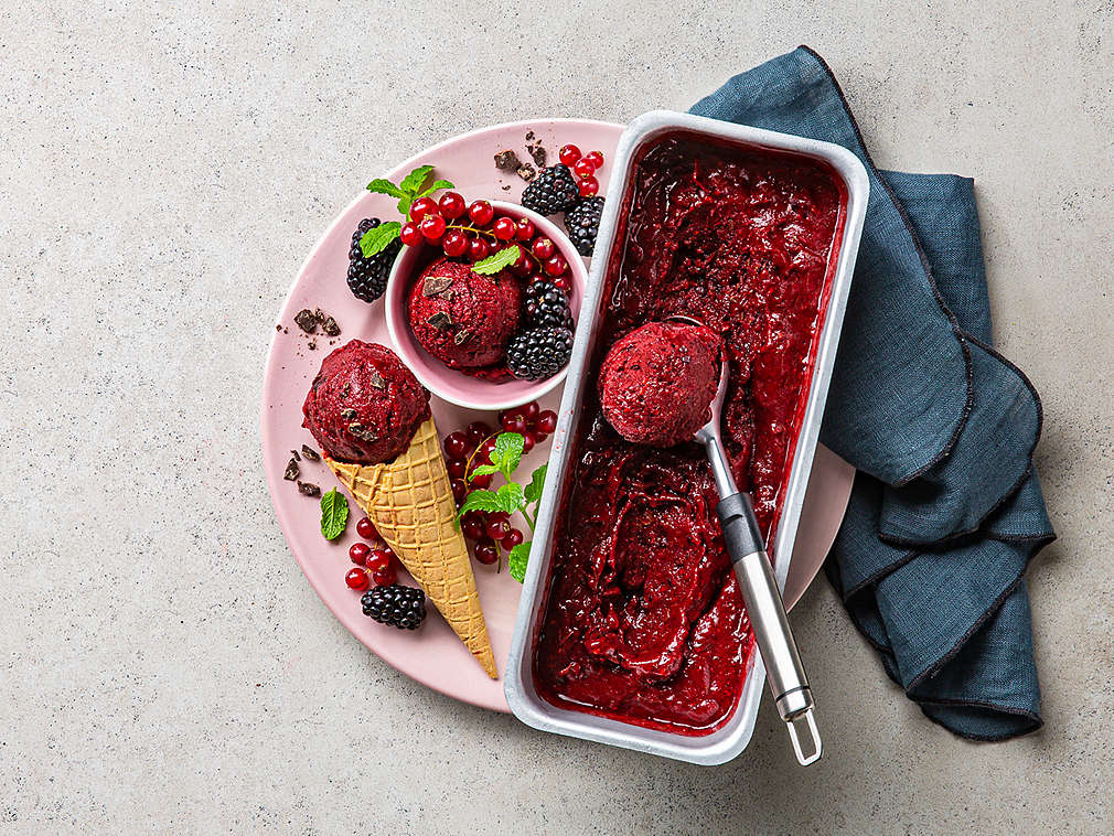 Brombeer-Sorbet mit Schokochunks, daneben eine Eiswaffel