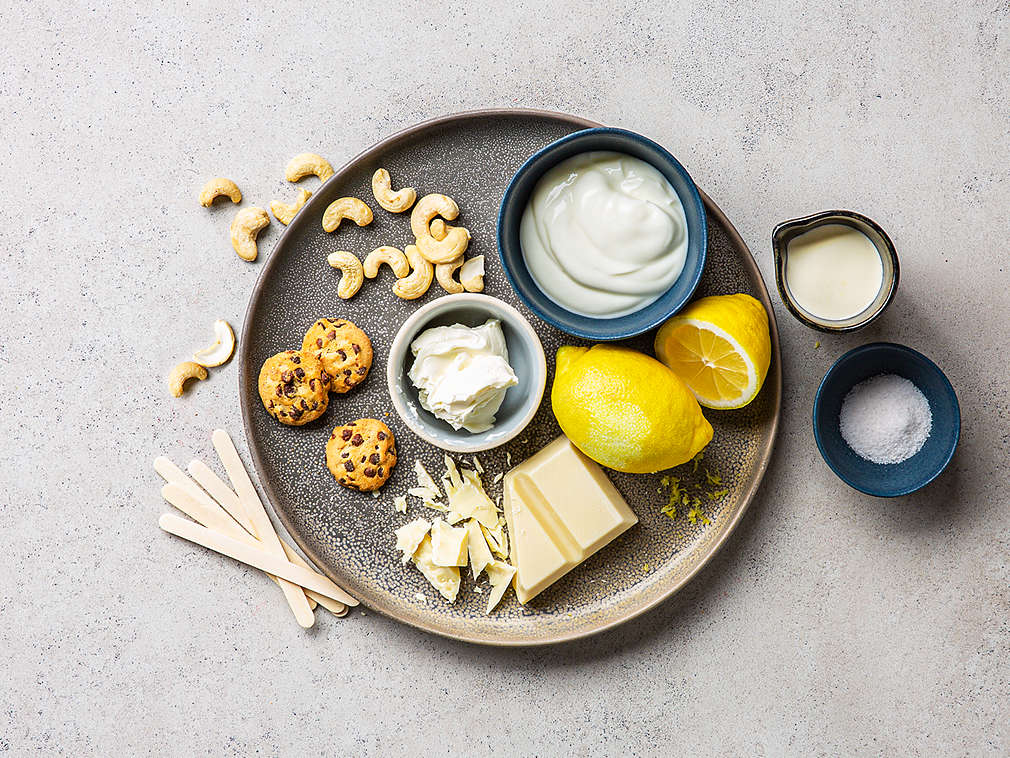 Teller mit Cookies, Cashewkernen, Zitronen, weißer Schokolade, Joghurt